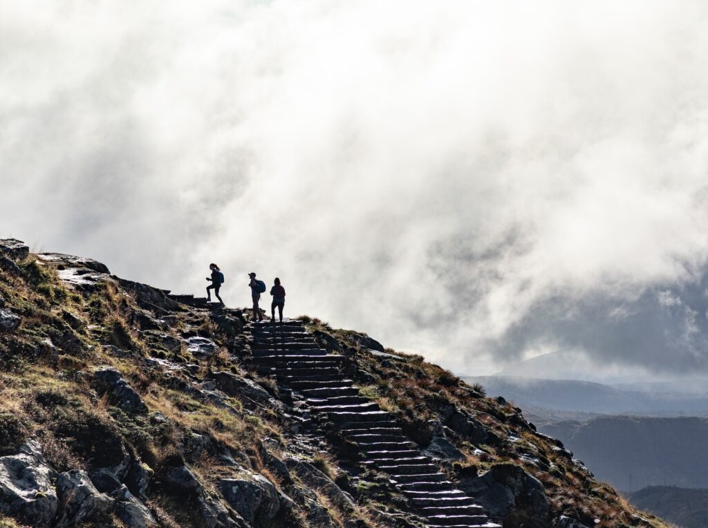 person standing on rocky mountain under cloudy sky during daytime