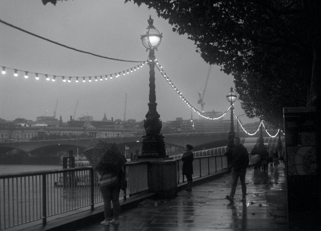 grayscale photo of people walking on bridge