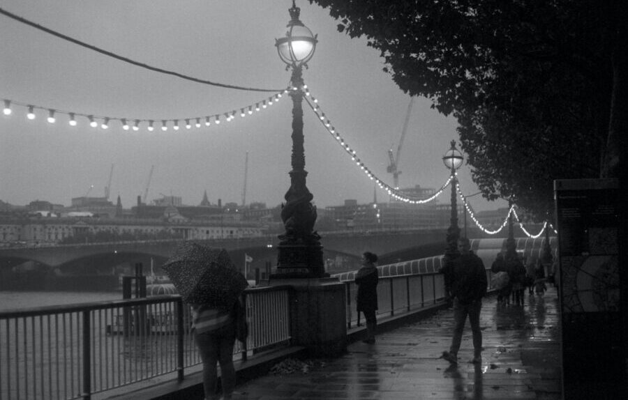 grayscale photo of people walking on bridge