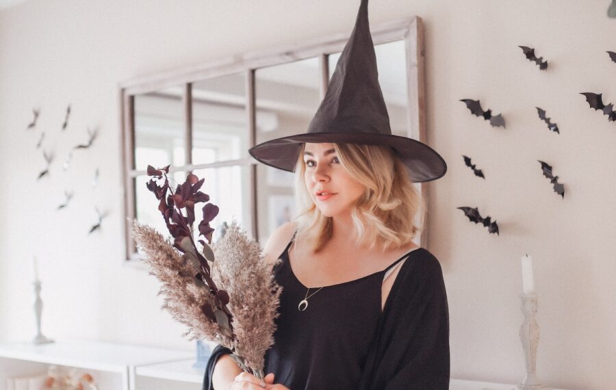 woman in black v neck long sleeve shirt and black hat standing near white wall