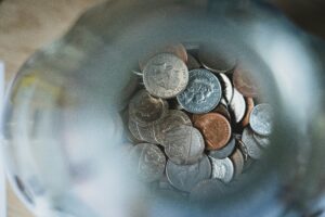 Aerial view of assorted coins inside a glass jar, embodying the quiet weight of financial stress.