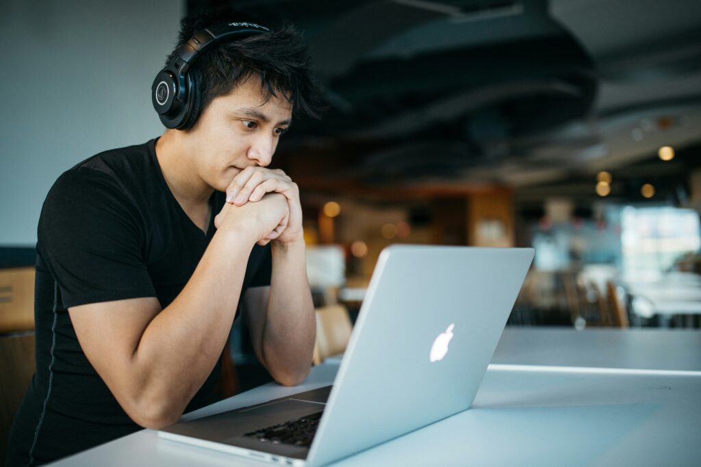 A person wearing headphones is focused intently on a laptop screen in a modern indoor setting, immersed in digital reskilling efforts.