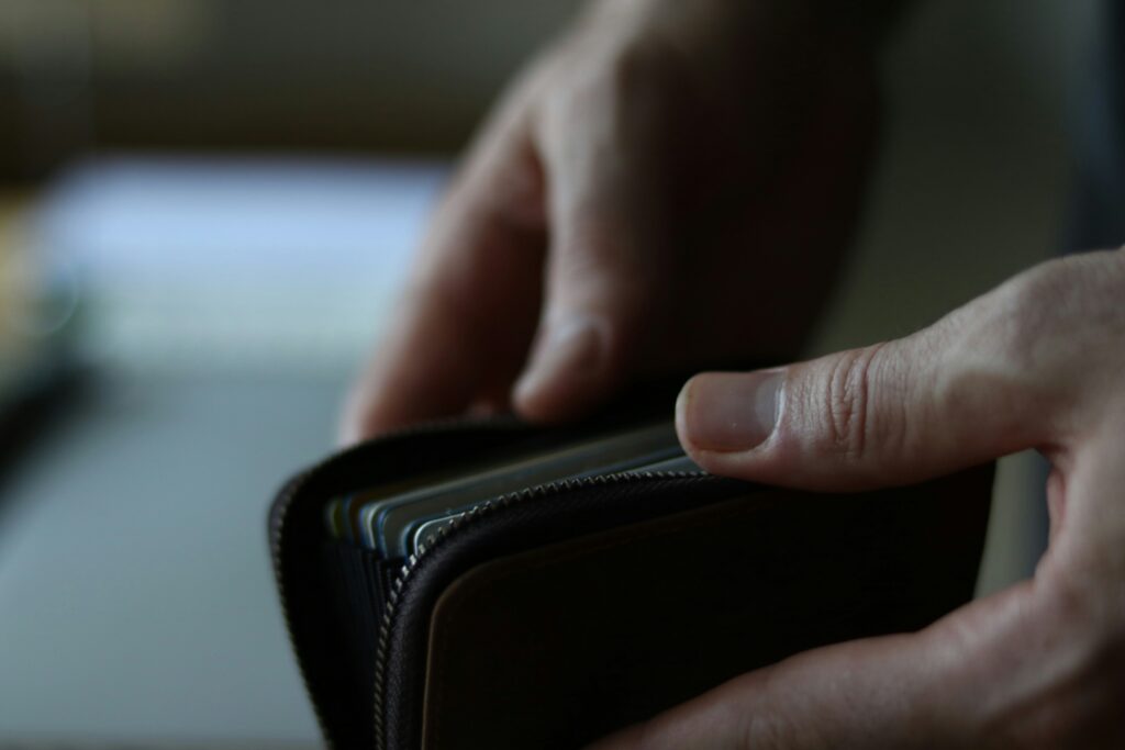Hands opening a zippered wallet filled with cards, meticulously managing finances.