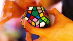 Hands skillfully manipulate a colorful dodecahedron puzzle cube, a delightful exercise in brain health.