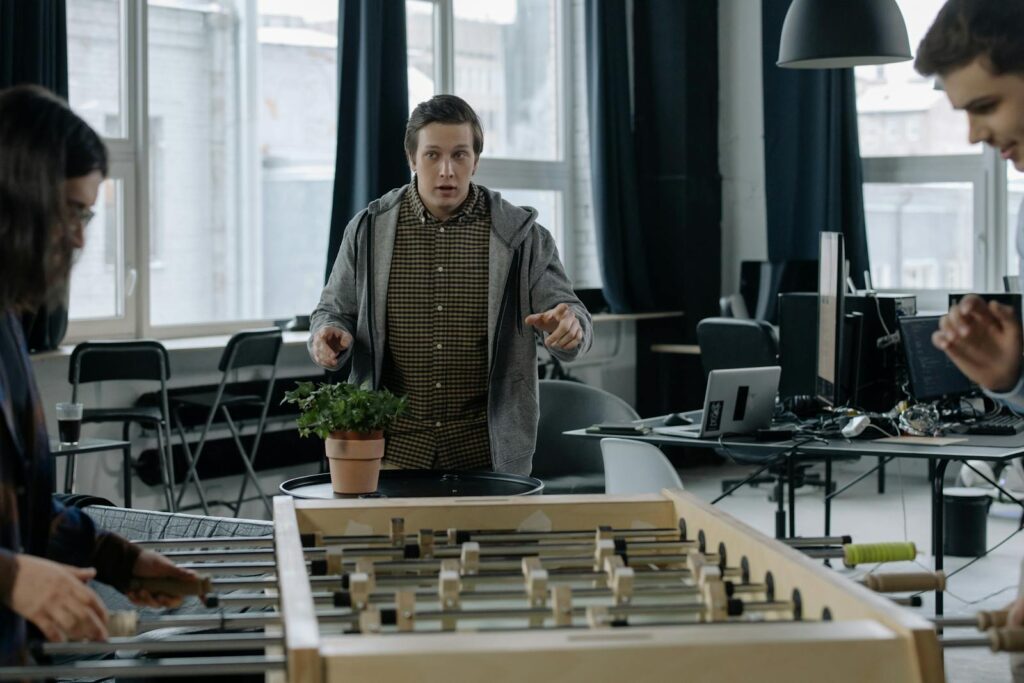 Young adults playing foosball in a trendy office with relaxed atmosphere and modern design.