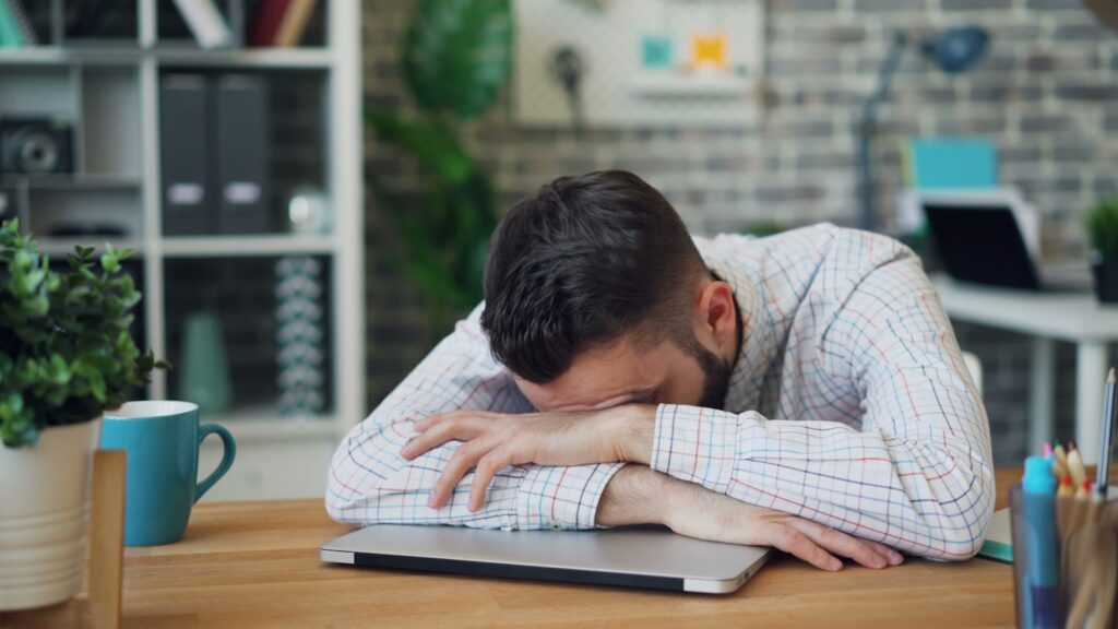 A man sitting at a desk with his head in his hands.