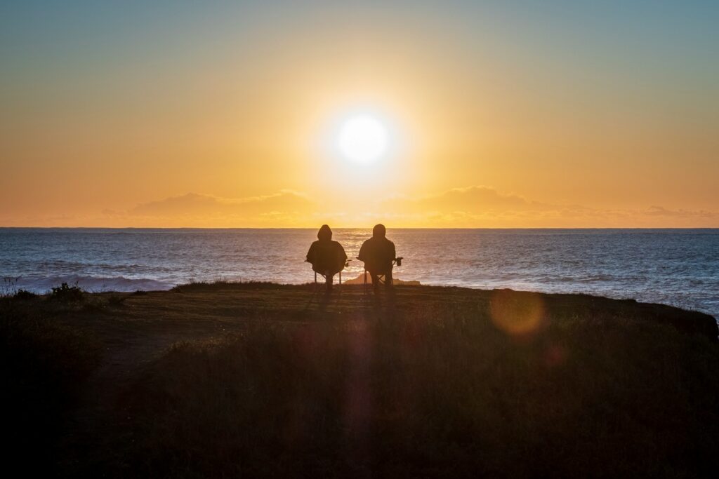 Two people sitting by the seashore.
