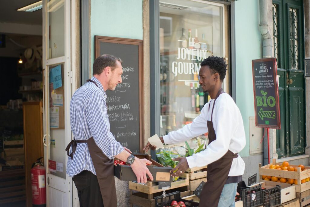 Two men arranging fruit and vegetables outside a store in Portugal.