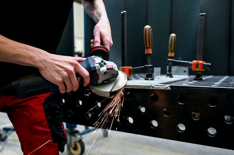 A man using a grinder on a piece of metal.