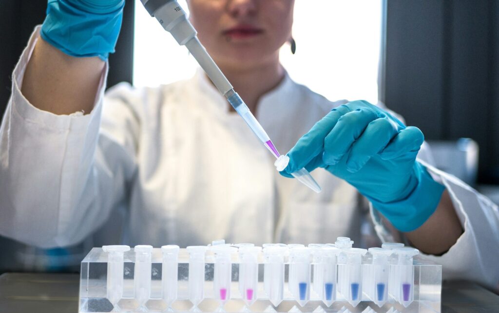 A person in a scientific laboratory holding a pipette.