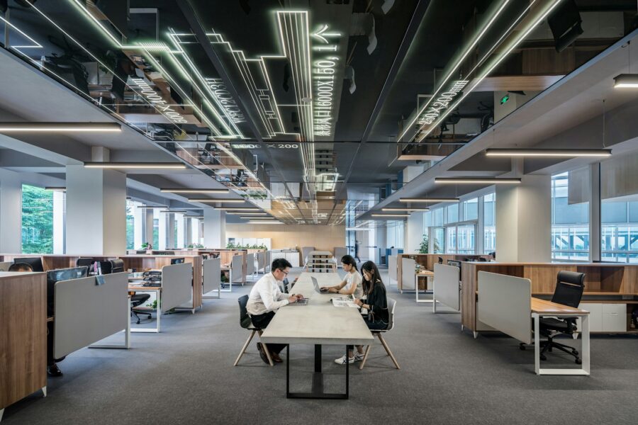 A wide view of an open office with people sitting around a table.