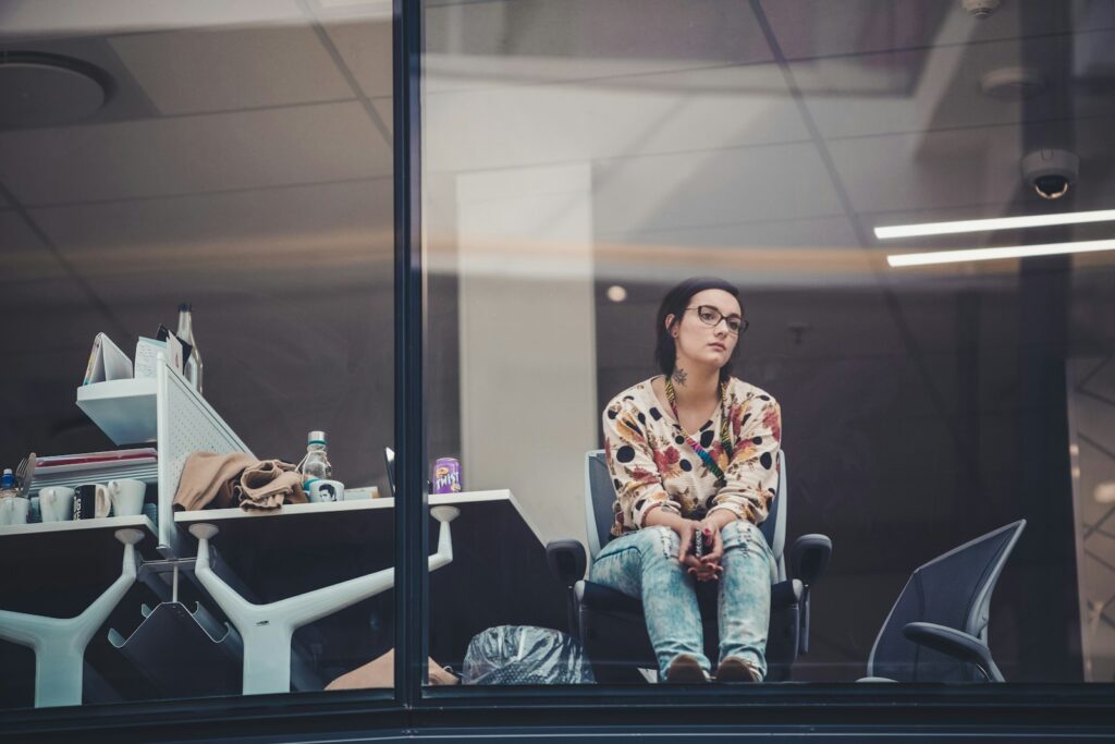A woman sits by an office table looking bored.