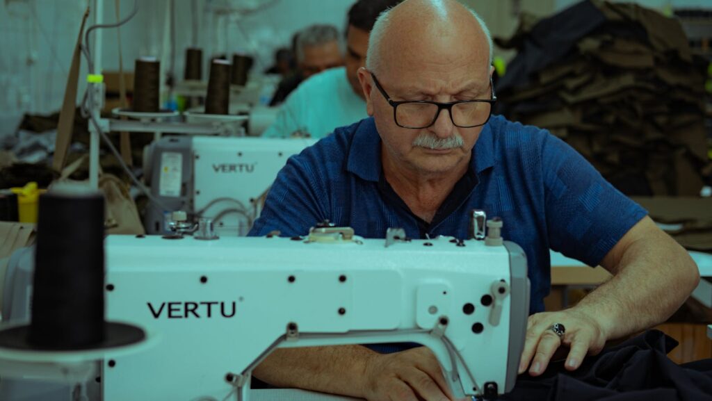 Elderly tailor focuses on garment sewing with a machine in Ankara workshop