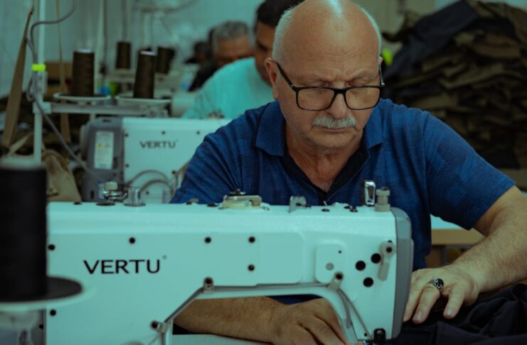 Elderly tailor focuses on garment sewing with a machine in Ankara workshop