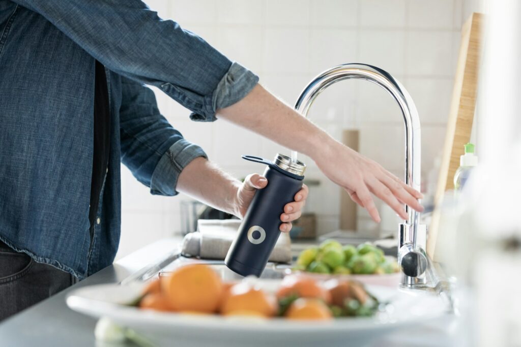 A person filling a water bottle at a sink.