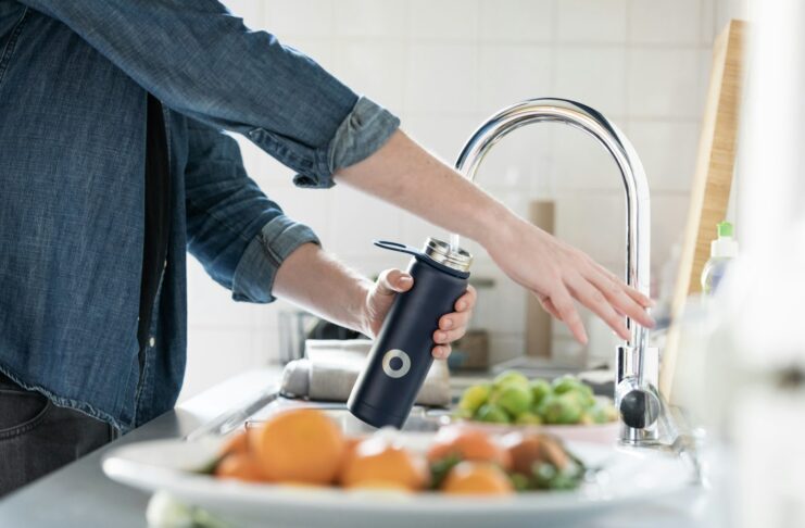A person filling a water bottle at a sink.