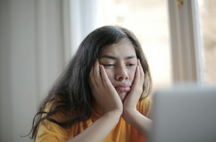Bored young woman at a table with laptop.