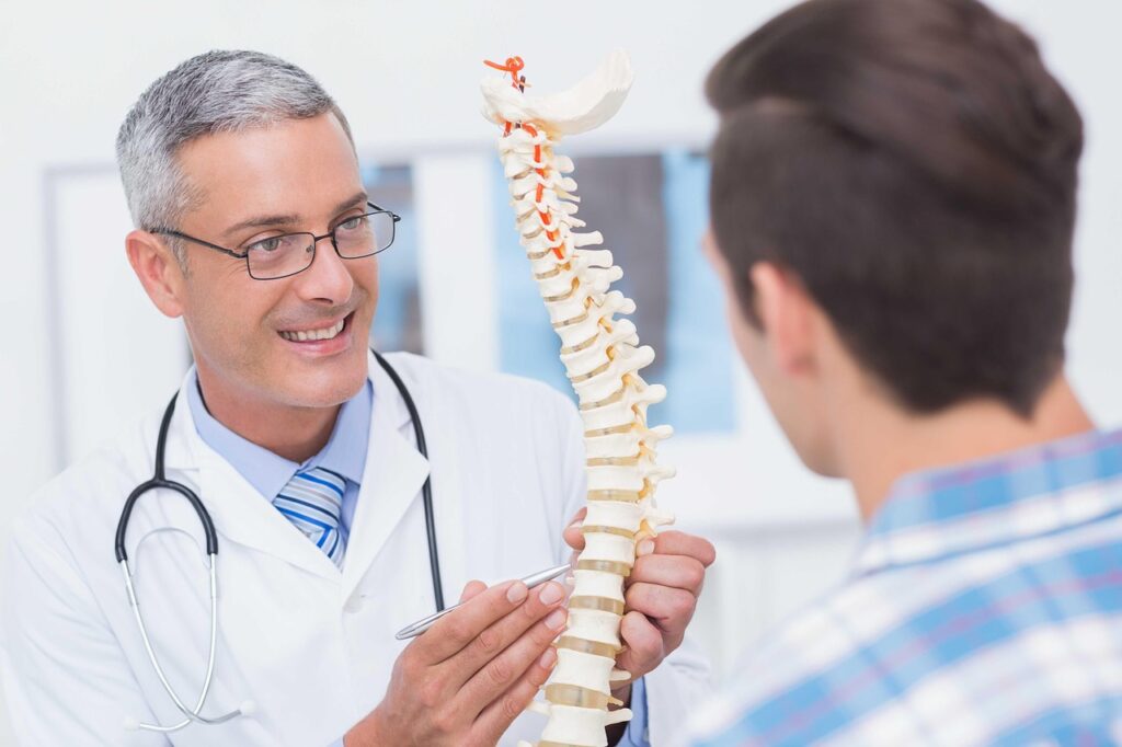 A doctor holding a model of a spine and with a patient.