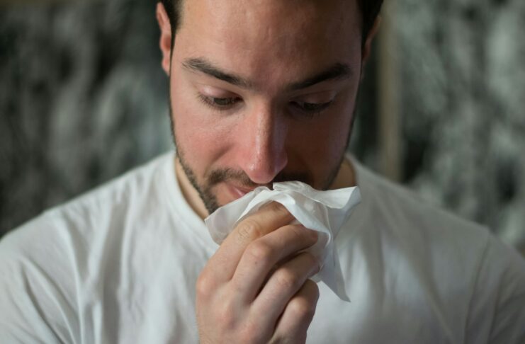 A man wiping his nose with a tissue.