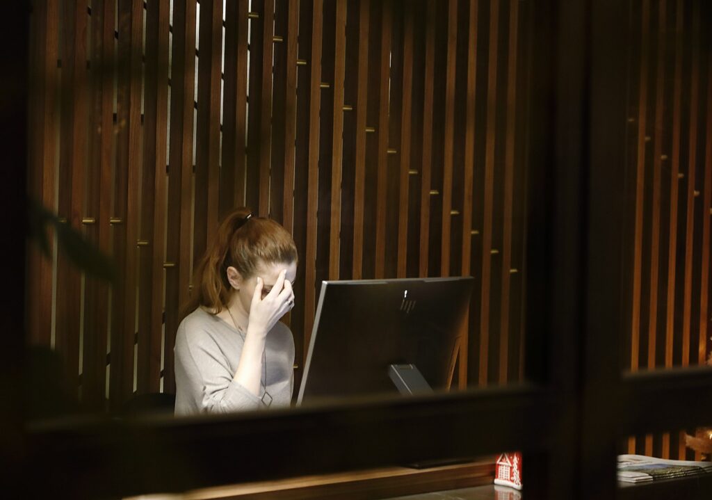 A woman sitting in front of a laptop computer looking stressed.