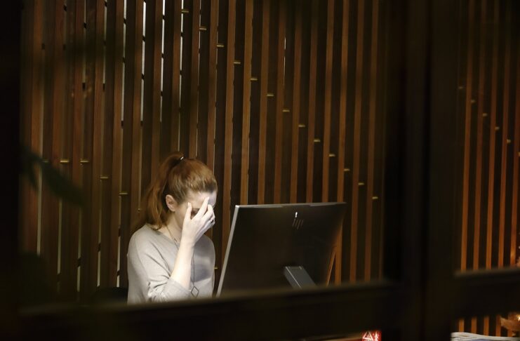 A woman sitting in front of a laptop computer looking stressed.