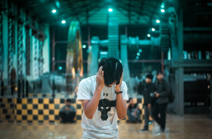 A young man with his hands over his ears in a noisy setting.