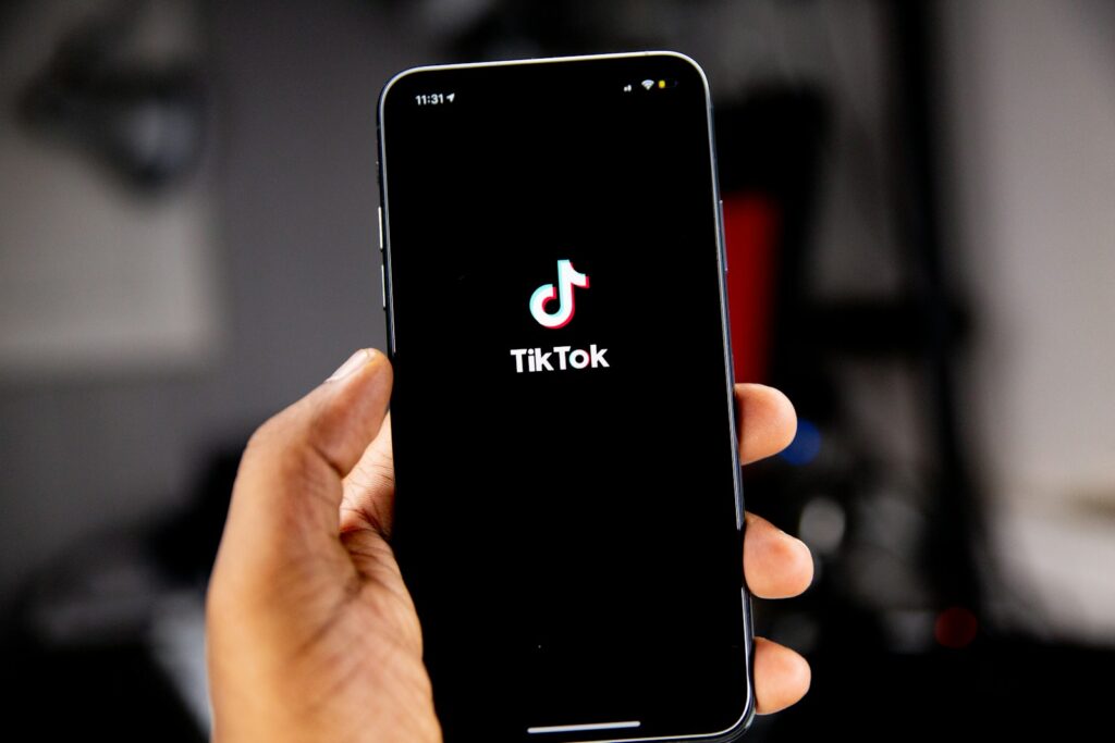 A person holding a smartphone with the TikTok app.