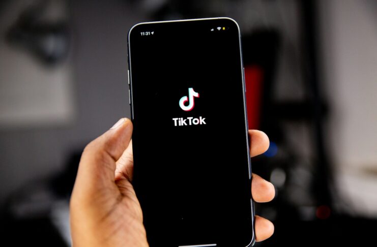 A person holding a smartphone with the TikTok app.