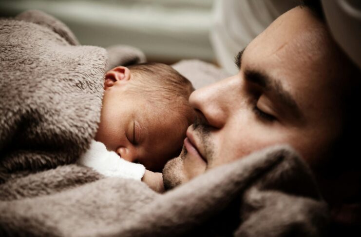 A touching close-up of a father and his baby peacefully napping together.