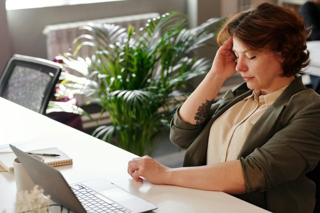 A woman feeling ill at her office desk while working on her laptop.