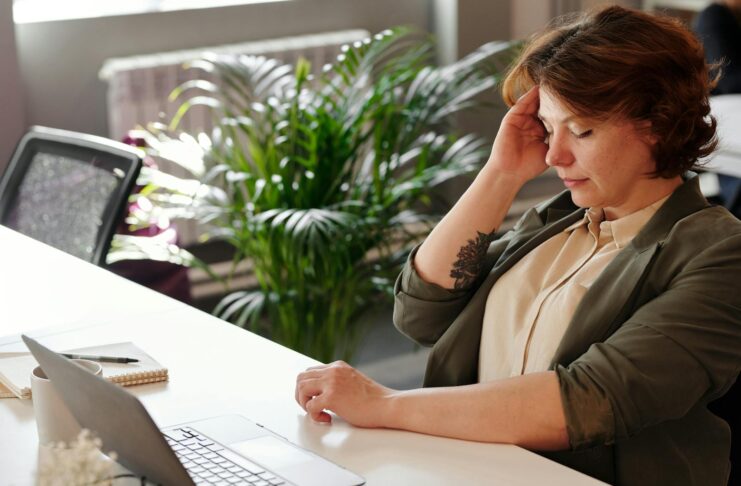 A woman feeling ill at her office desk while working on her laptop.