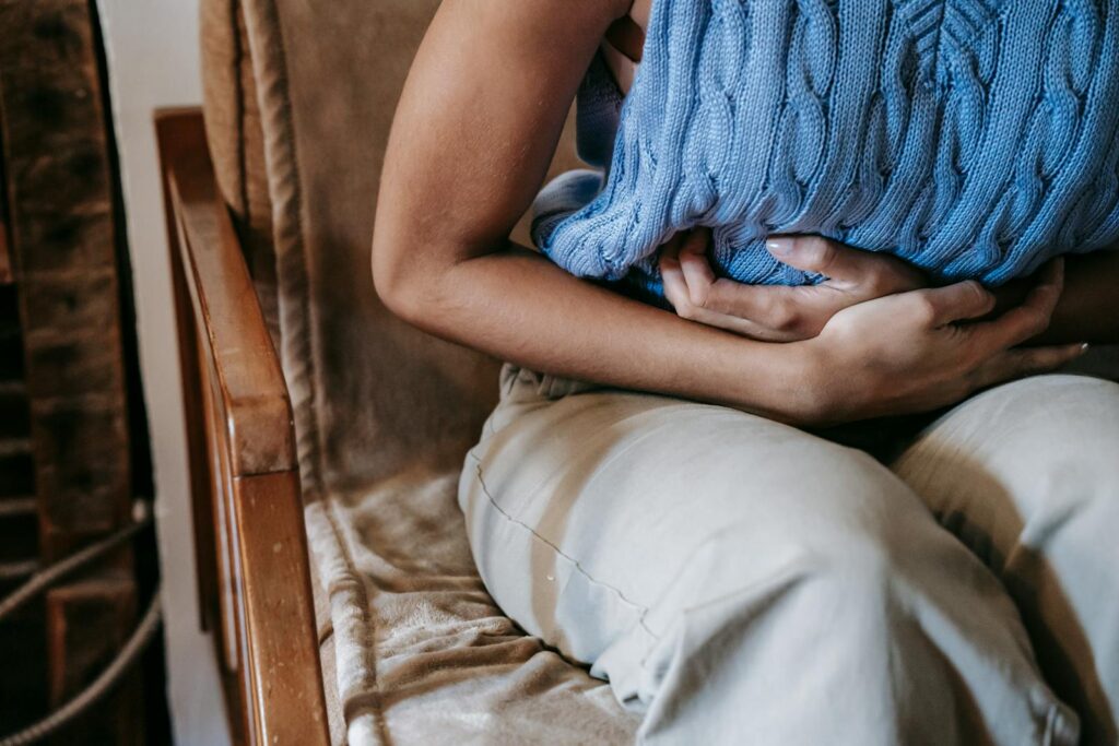 A woman sitting on a chair and doubled over with period pain.