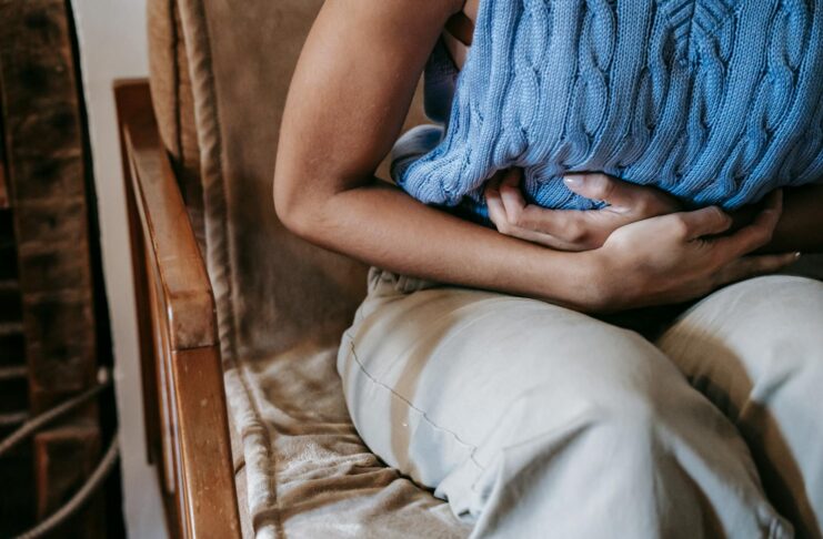 A woman sitting on a chair and doubled over with period pain.