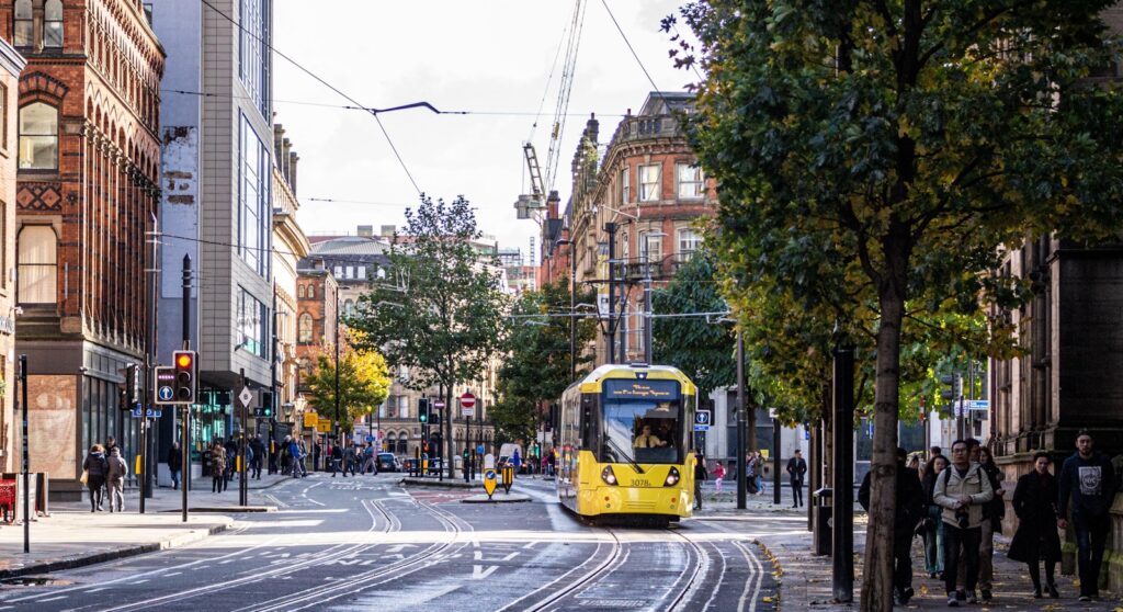 A Manchester street with people and a tram.