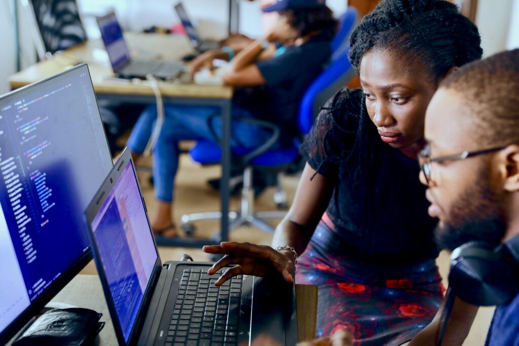 A man and woman looking at a computer screen in an office.