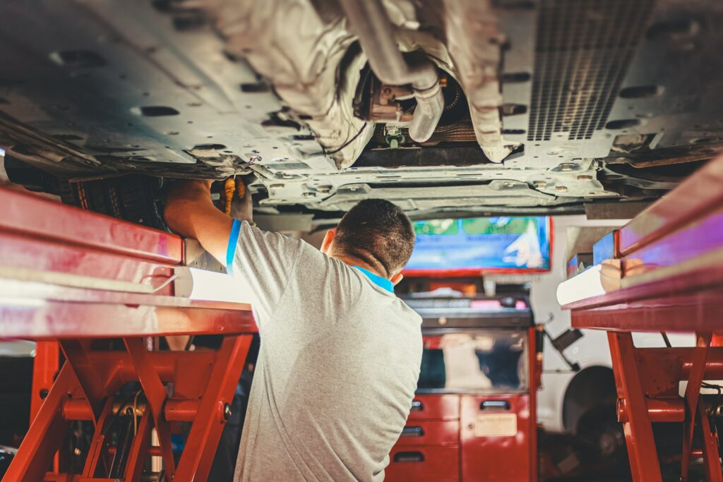 A mechanic works on a car in a pit.