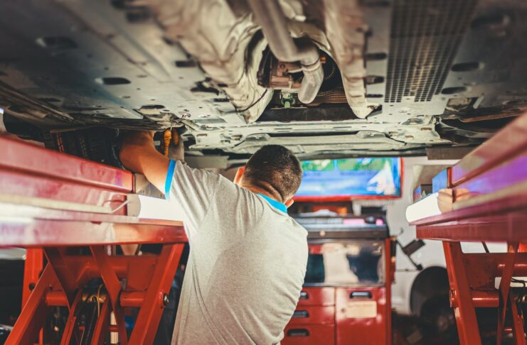 A mechanic works on a car in a pit.