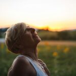 Menopause Hit Me Like a Truck – Changing My Diet Saved Me A middle-aged woman in white tank top looking at the sunset.