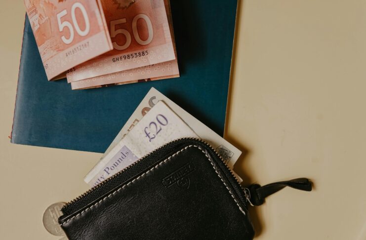 Pound notes beside and on a black wallet.