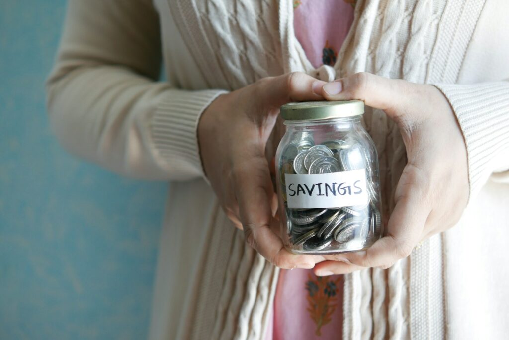 A woman holding a jar with savings written on it.