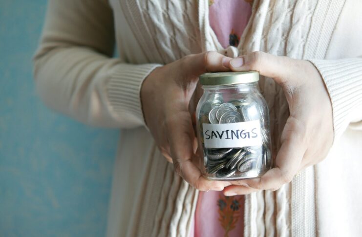 A woman holding a jar with savings written on it.