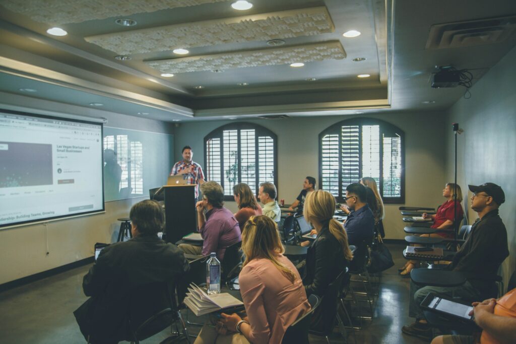 A group of people in a room with a projector screen.