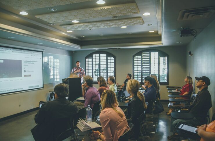 A group of people in a room with a projector screen.
