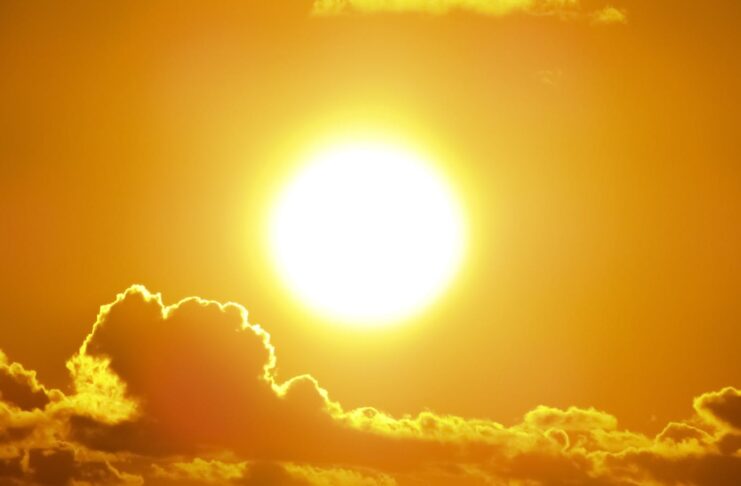 A stunning view of the sun shining through clouds at sunset, casting a warm glow.