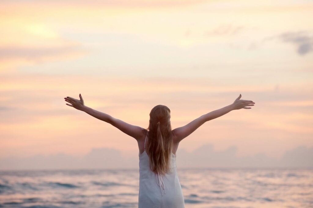 A woman enjoying a serene sunset on a beach.