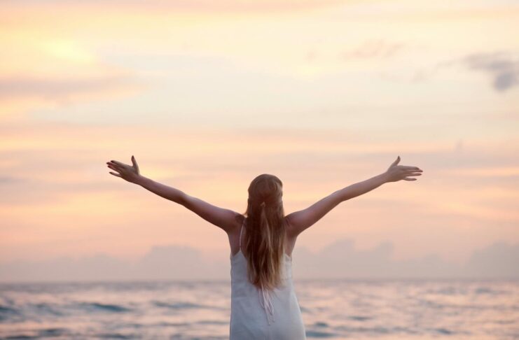 A woman enjoying a serene sunset on a beach.