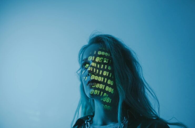 A woman with binary code lights projected on her face, symbolizing technology.