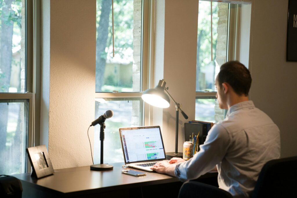 A man working from home, on a laptop and in front of a window.