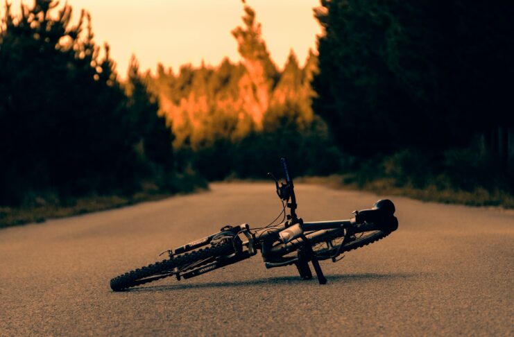 A bike laying on its side on the side of the road.