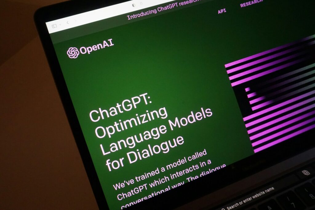 A laptop displays a webpage of OpenAI, creator of ChatGPT.